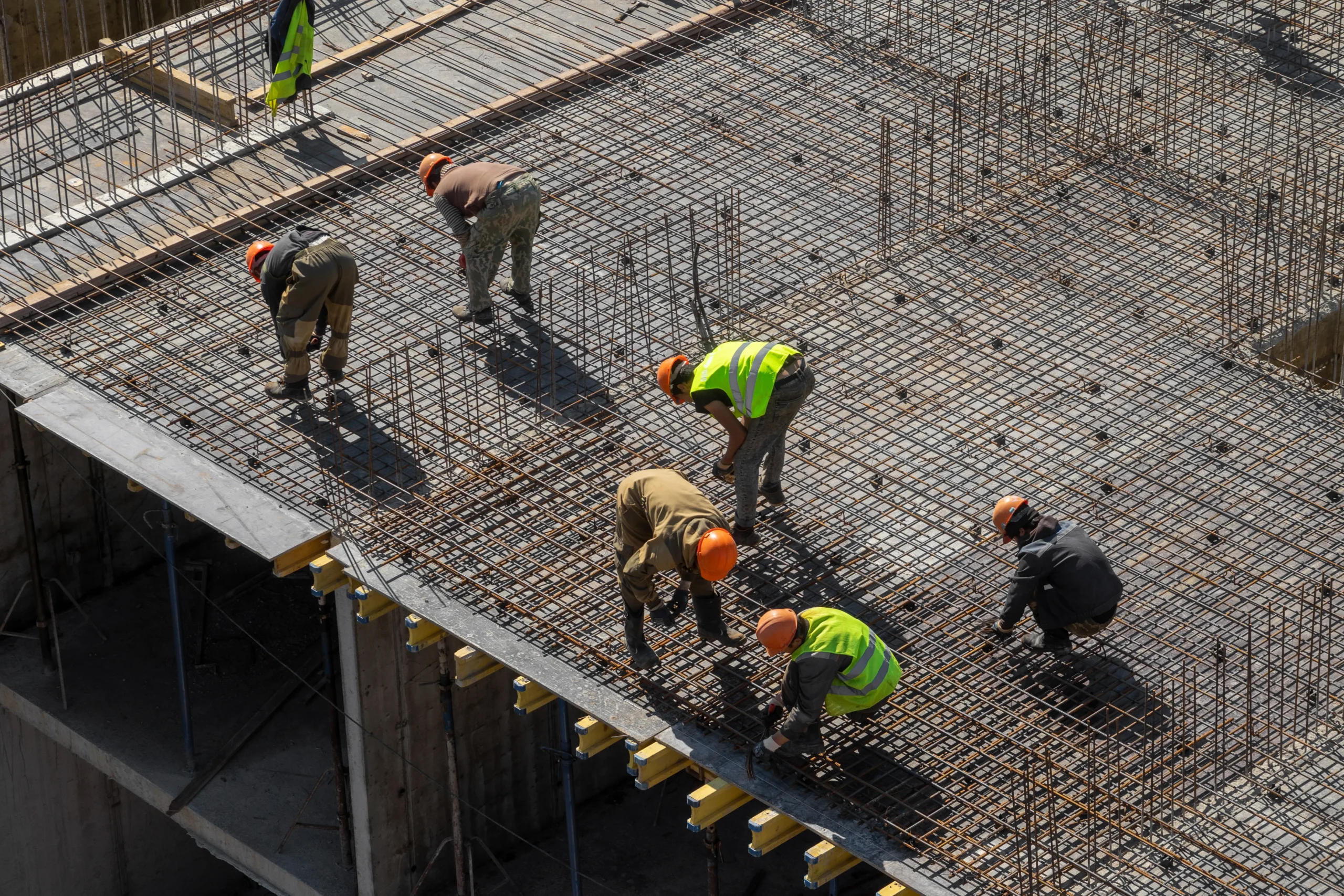 Equipe técnica executando conferências de armaduras e posicionamento estrutural antes da concretagem de lajes em obra.