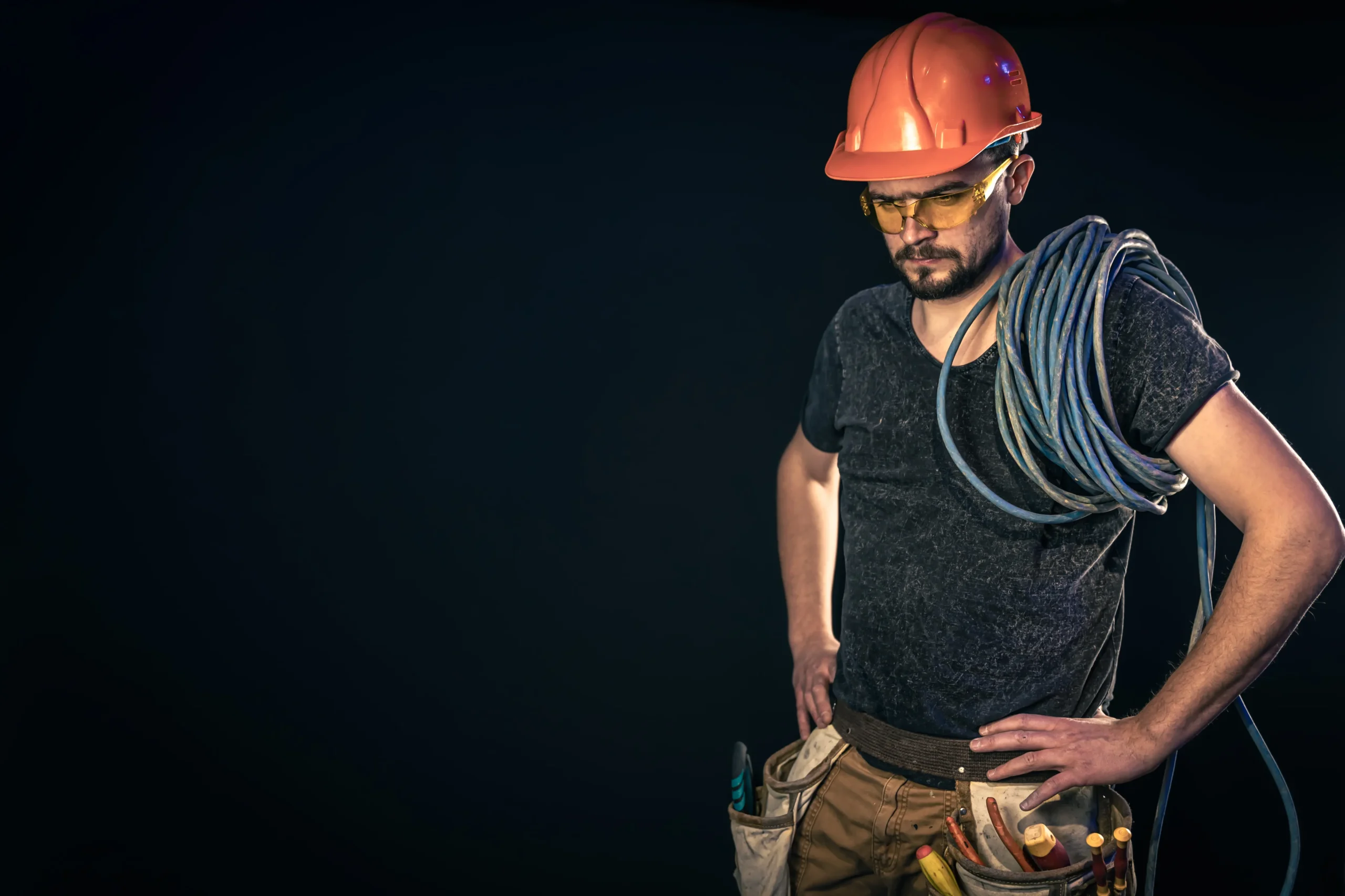 An electrical worker wearing PPE carries cables, showing readiness and risk awareness in line with NR-10 safety practices.