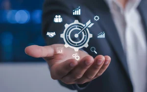 Ícone central de “alvo/engrenagem”, indicando gestão de performance e melhoria contínua, típico da QP (validação de desempenho, metas, indicadores e controle).