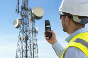 Profissional realizando medição de campo próximo a antenas e enlaces de telecomunicações. A cena representa avaliação de exposição a radiofrequência, típica de inspeções em áreas com emissores de RF e micro-ondas.