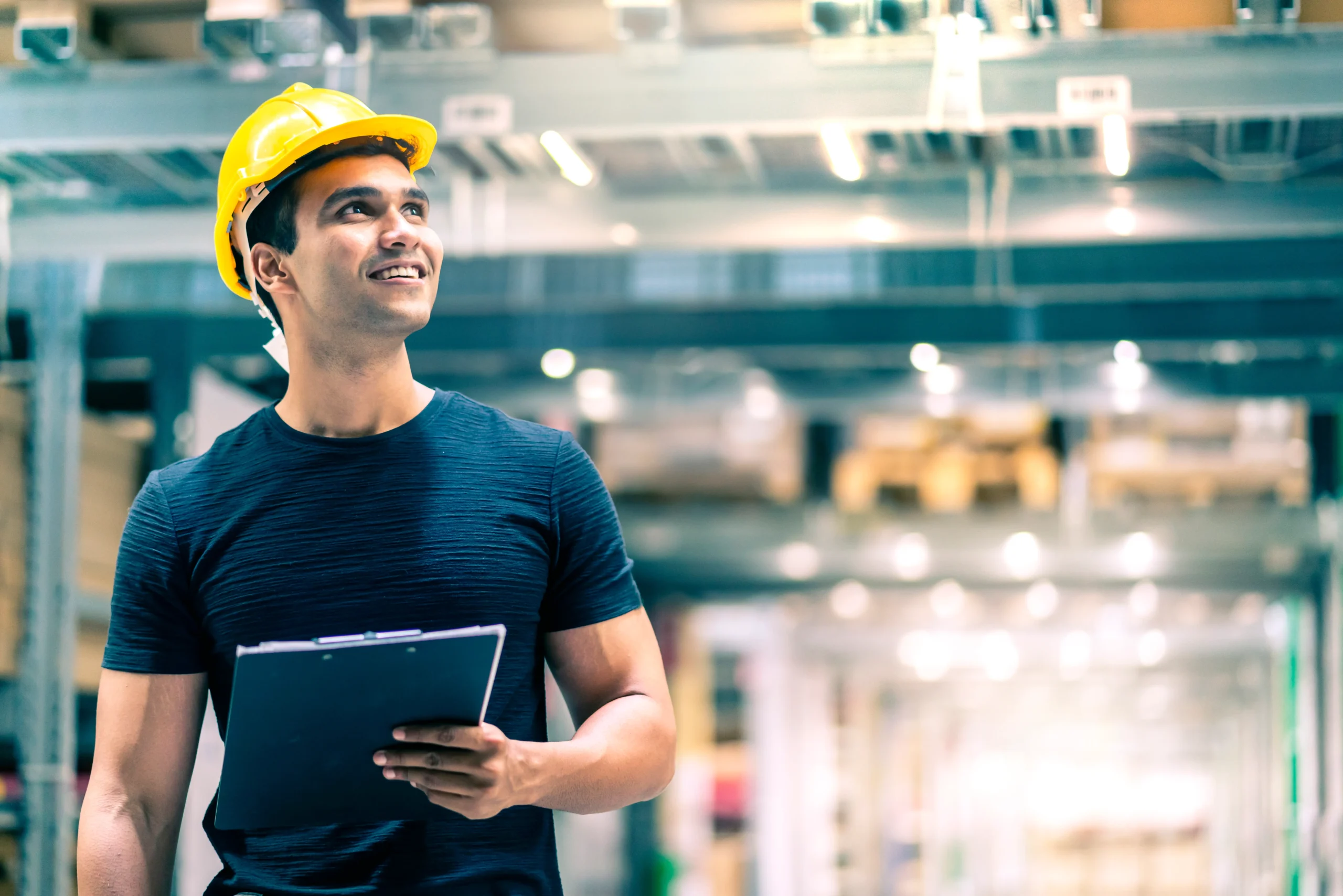 A professional wearing a hard hat and holding a clipboard observes the production area, indicating supervision, risk assessment, and verification of operational compliance. The image reflects effective technical training and the instructor’s responsibility to convey information accurately.