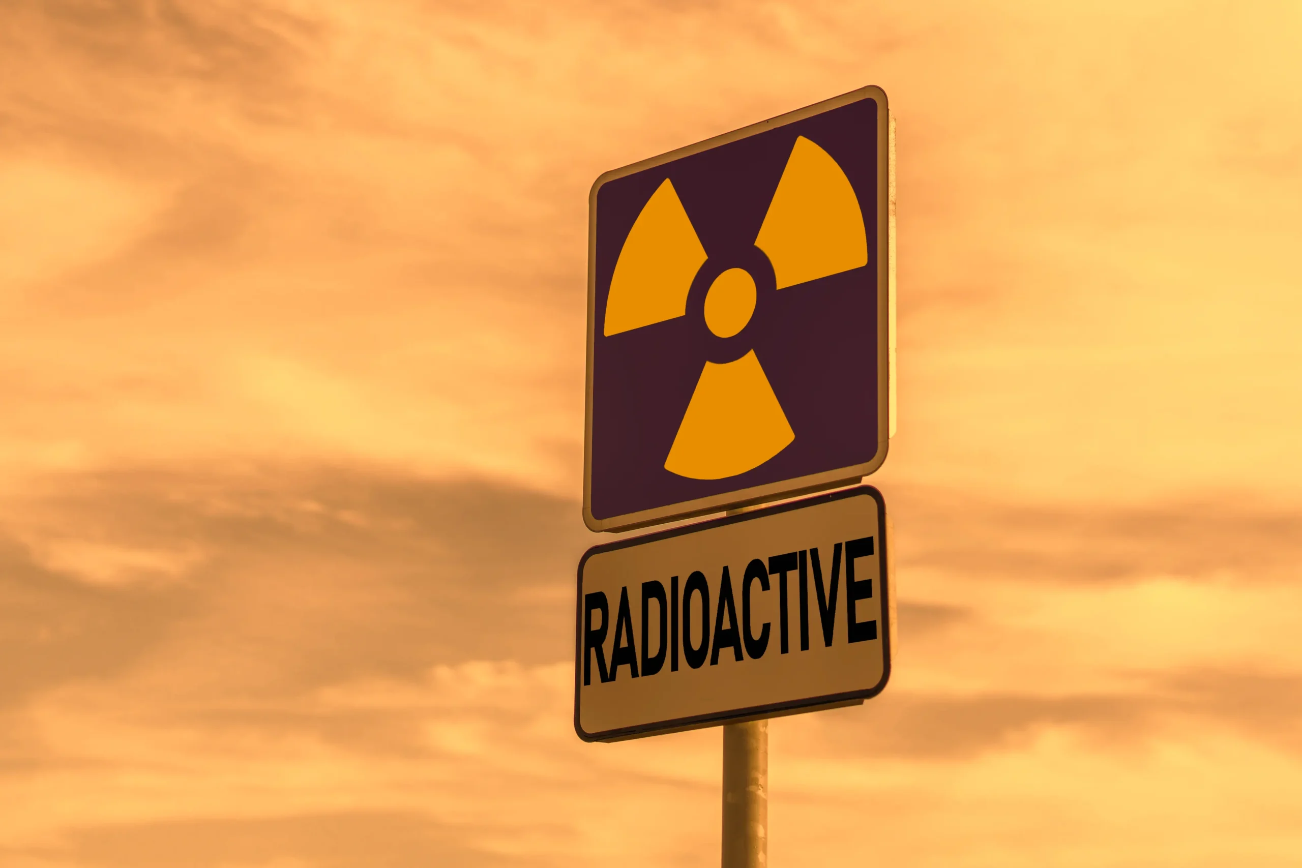 Placa de alerta de radiação com identificação textual. Apesar do termo “radioactive” remeter a radiação ionizante, a imagem funciona como referência visual de comunicação de risco e sinalização, tema essencial em ambientes com radiações não ionizantes e controle ocupacional.