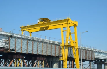 DESTAQUE Pórtico rolante industrial de grande porte aplicado em montagem estrutural, evidenciando robustez da viga principal, estabilidade dos apoios e precisão no sistema de içamento para operações críticas de carga pesada.