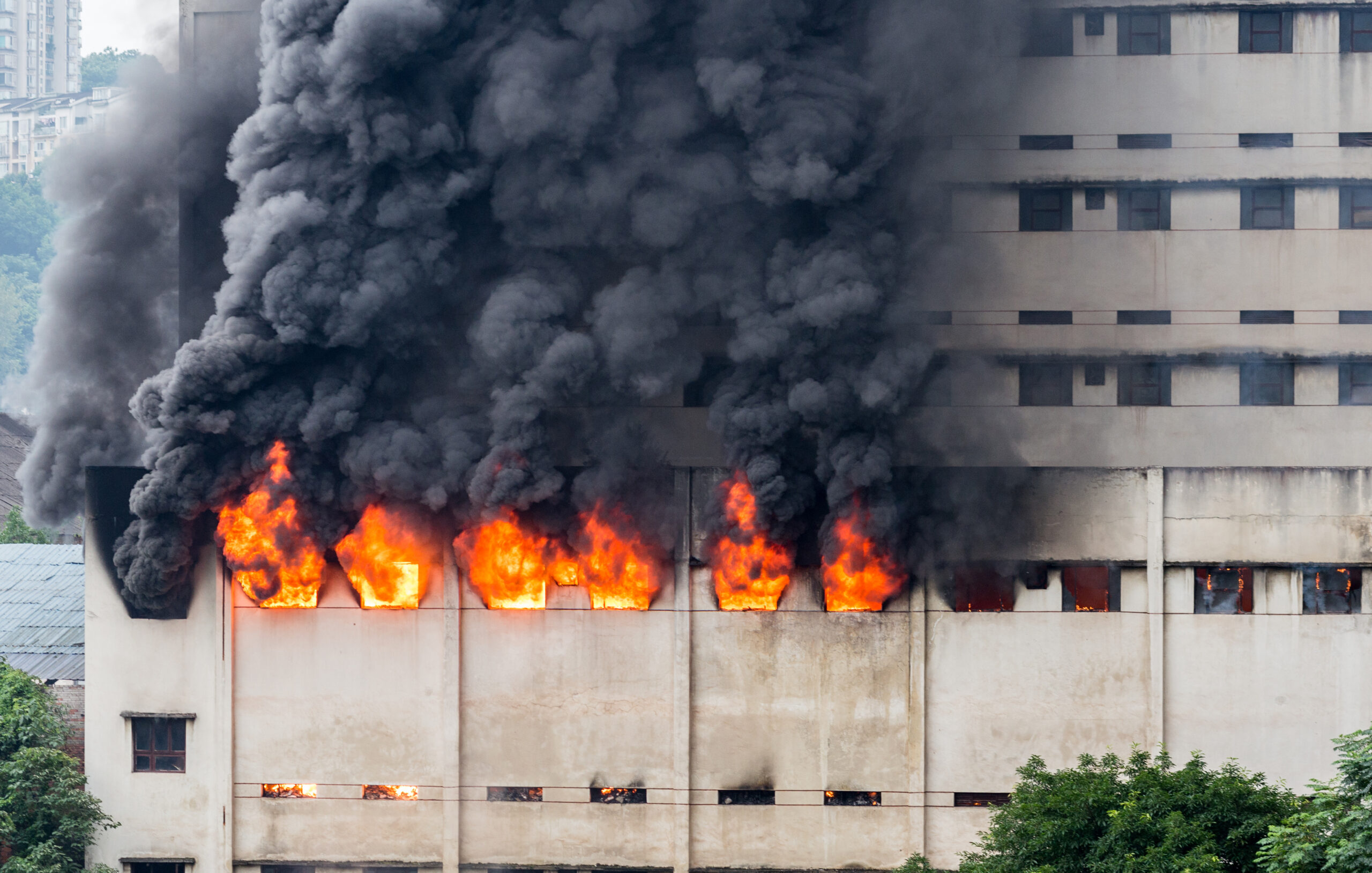 Incêndio estrutural com propagação vertical e emissão de fumaça densa, caracterizando cenário de potencial perda total e elevada taxa de liberação de calor.