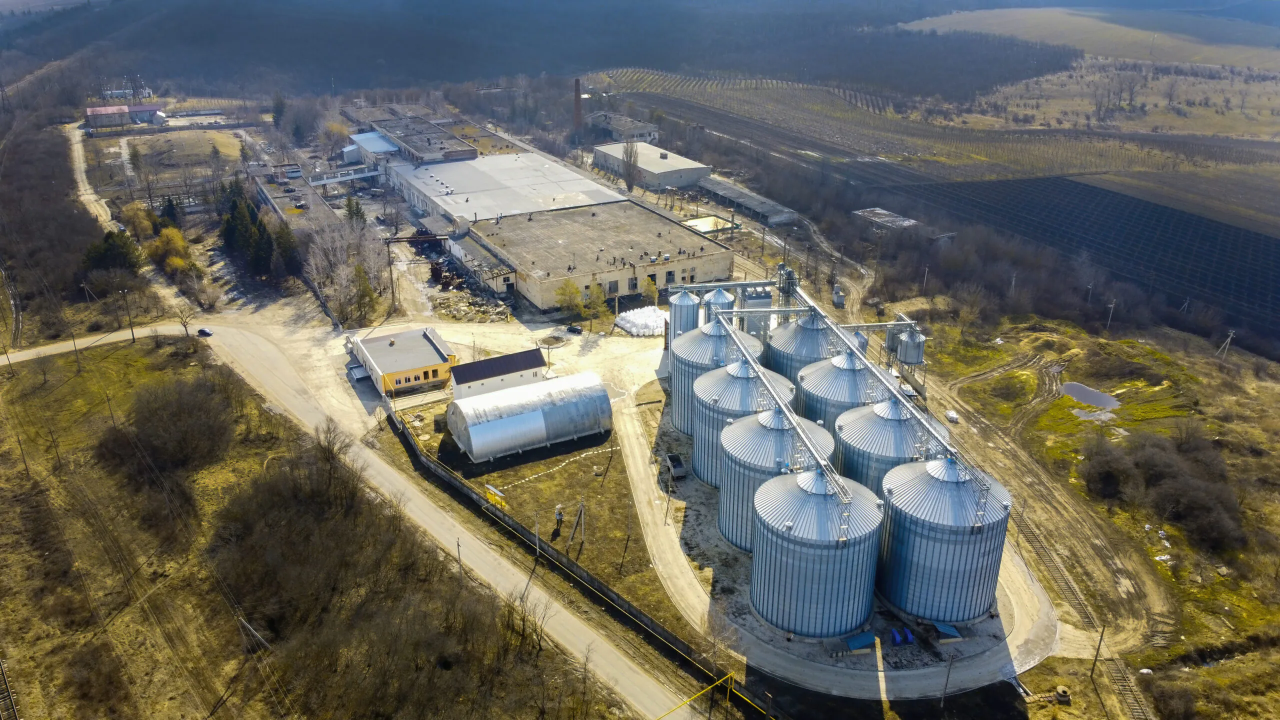 Área de armazenamento externo de produtos químicos ou combustíveis em tambores metálicos de 200 litros, com organização por empilhamento horizontal e segregação por cor. - Curso SASC Sistema Armazenamento Subterrâneo de Combustível
