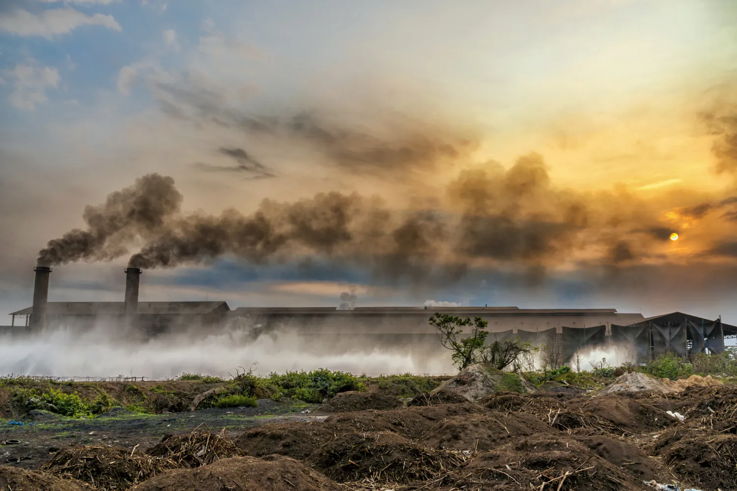 Instalações industriais lançando contaminantes no ar, com potencial impacto direto sobre o solo e aquíferos subterrâneos. Diagnóstico preliminar e avaliação de risco são cruciais para evitar passivos ambientais ocultos.