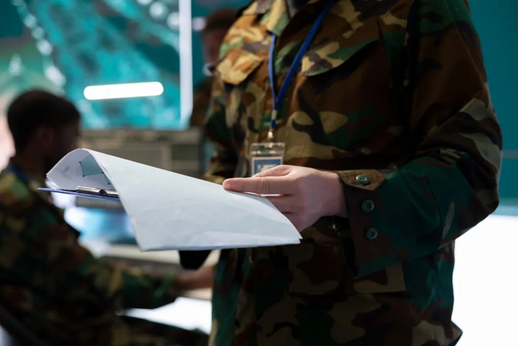 Exército analisando documento; avaliação de conformidade e segurança dos produtos controlados, garantindo que atendam às normas estabelecidas pelo Exército Brasileiro. - Consultoria para Obtenção de Licença de Produtos Controlados