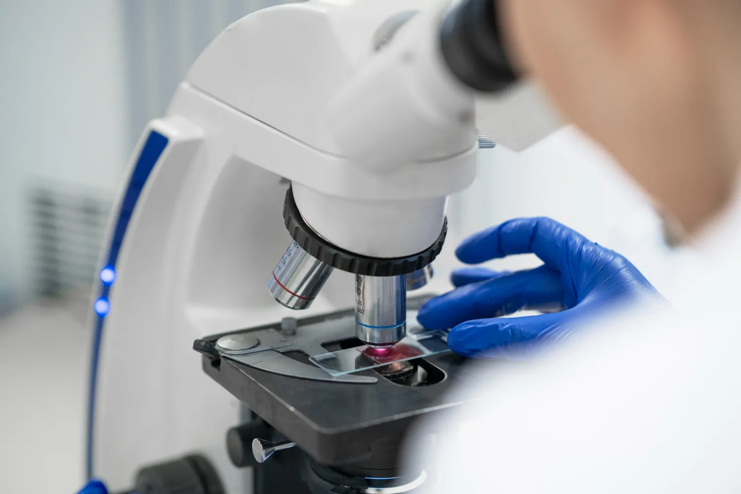 Técnico realiza avaliação técnica para detecção de amianto em laboratório, utilizando um microscópio de alta precisão para análise de amostras - Detecção de Amianto.
