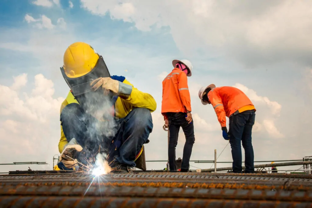 Trabalhadores a trabalhar no canteiro de obras com equipamentos de segurança durante execução das atividades. - Consultoria NR 01