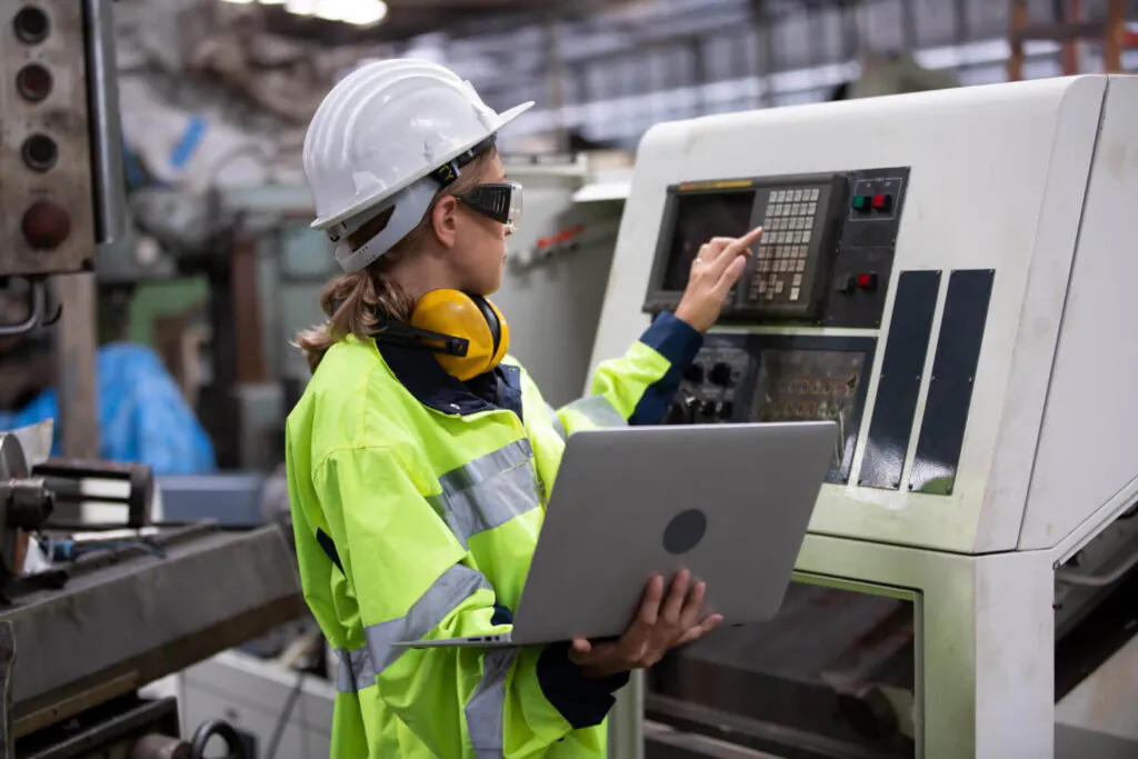 Imagem de um operador de máquina em uma fábrica, utilizando Equipamentos de Proteção Individual (EPIs) enquanto segue as diretrizes de segurança previstas na NR 12.