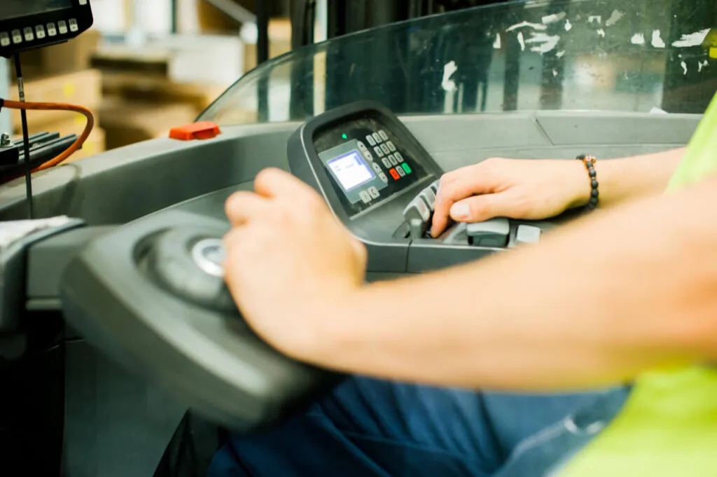 Ambiente industrial com operadores de máquinas em ação, evidenciando o uso de dispositivos de segurança e práticas para minimizar riscos e acidentes.