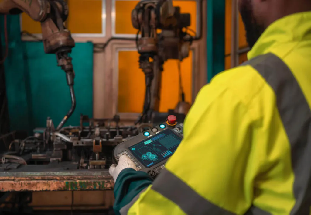 trabalhador em treinamento, manuseando uma máquina com equipamentos de proteção, destacando a importância do conhecimento para operar de forma segura, conforme a NR 12.