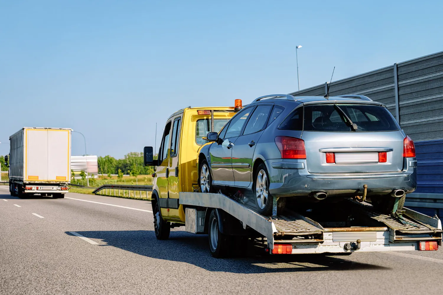Guincho plataforma realizando o transporte seguro de veículo imobilizado em rodovia, garantindo remoção eficiente e conforme normas de segurança. - Laudo Guincho Reboque.
